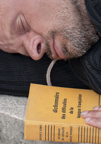 A bum sleeping in front of Notre-Dame with a book entitled, &laquo;Dictionnaire des difficult&eacute;s de la langue fran&ccedil;aise&raquo; (Dictionary of the difficulties of the French language), by Adolphe V. Thomas. Dozens of people were gathered around him, feeding sparrows and he slept through it all.