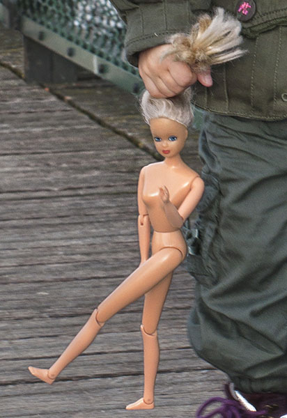 A little girl holding a Barbie doll by the hair on a cold winter day with temperatures of 34&deg;F on pont des Arts.