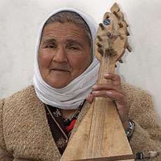 An elderly Bulgarian woman playing a gadulka next to the Pompidou Center.