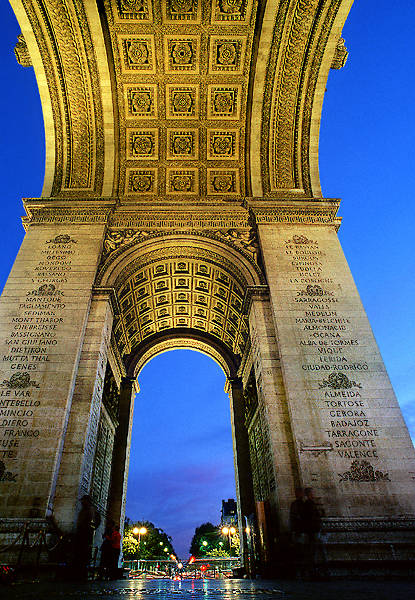 Arches and pillars of l’Arc de Triomphe at night.