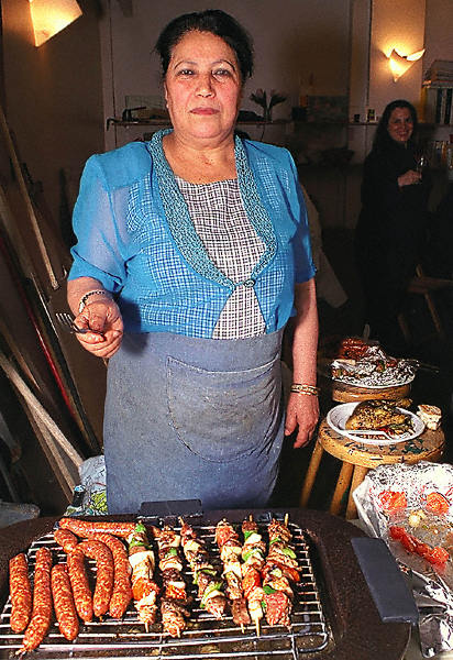 An Algerian woman cooking skewers and merguez in Belleville.
