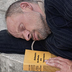 Un homme sans domicile fixe dormant sur le livre intitulé «Dictionnaire des difficultés de la langue française» devant Notre-Dame.