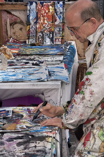 Un artiste-peintre avec ses œuvres devant le Centre Pompidou.