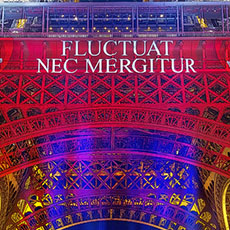 The Eiffel Tower with the city of Paris’ slogan, Fluctuat nec mergitur projected on it at night.