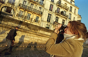 Une jeune femme en train de prendre des photos sur l’île Saint-Louis avec son reflex Canon argentique.