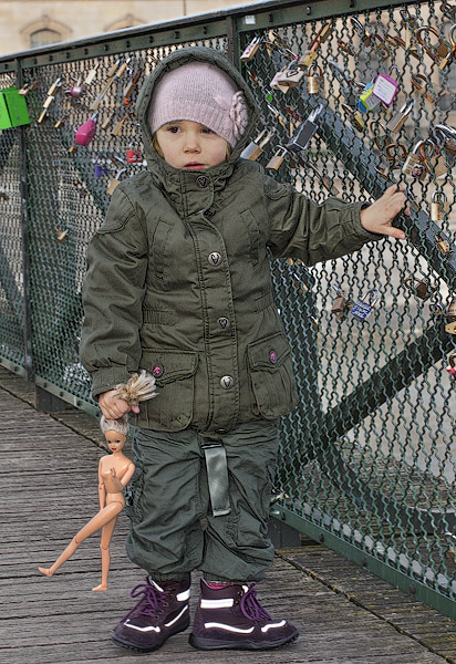 A little girl holding a Barbie doll by the hair on pont des Arts.