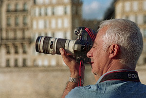 A photo workshop participant taking pictures of Notre-Dame from quai de la Tournelle with a Canon DSLR.