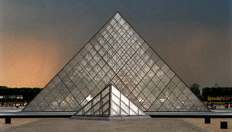 La grande pyramide du Louvre devant des nuages oranges d’une tempête.