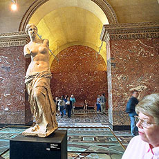 Besökaren swirl runt omkring en staty på den Louvre