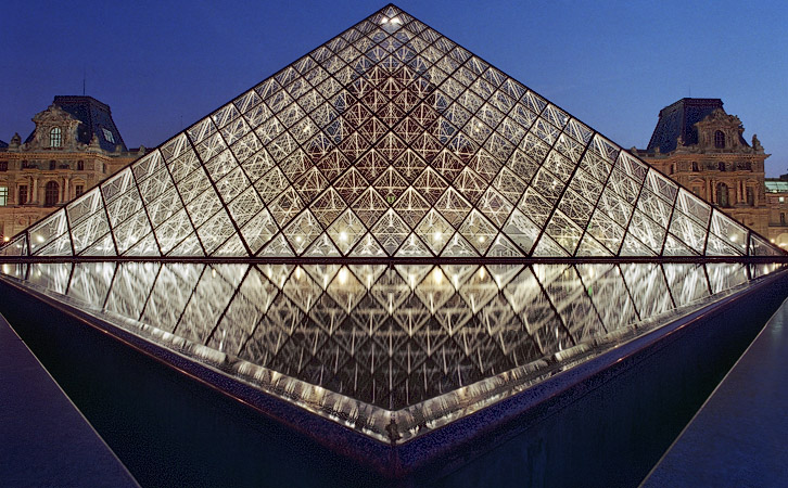 La Grande Pyramide du Louvre entourée des bassins d’eau triangulaires le soir.