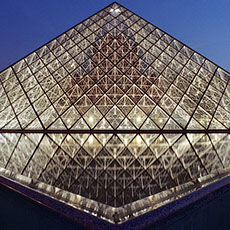 Des bassins d’eau triangulaires la Grande Pyramide du Louvre le soir.