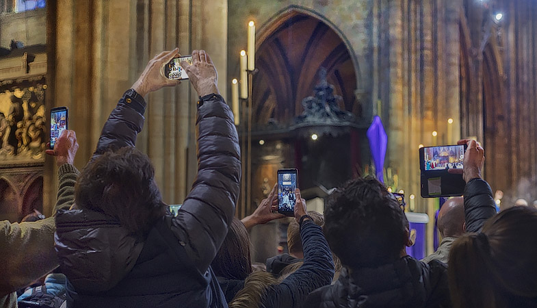 Des gens prenant des photos avec leur téléphones lors de la messe dans la cathédrale Notre-Dame trois jours avant l’incendie du 15 avril 2019.