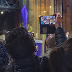 Des gens prenant des photos avec leur téléphones lors de la messe dans la cathédrale Notre-Dame trois jours avant l’incendie du 15 avril 2019.