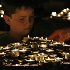 A boy with prayer candles inside Notre-Dame.