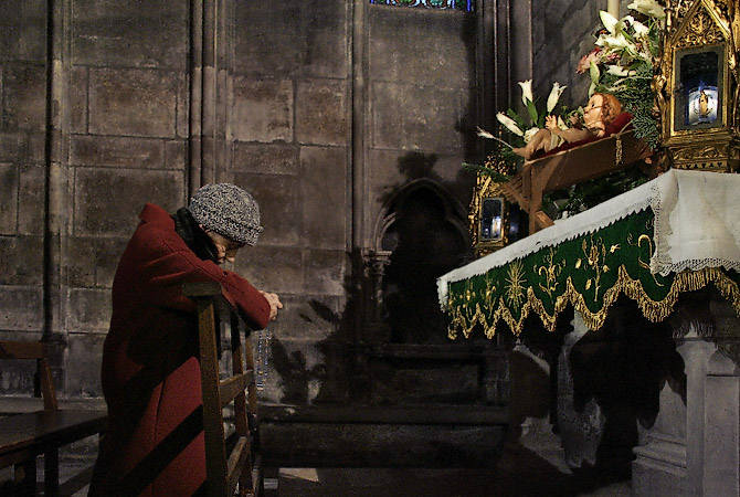 Une veille femme en train de prier dans la cathédrale Notre-Dame.
