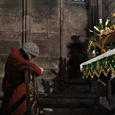 An elderly woman praying inside Notre-Dame cathedral.