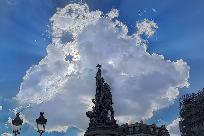 Le soleil et des nuages derrière la sculpture dans la place de Clichy.