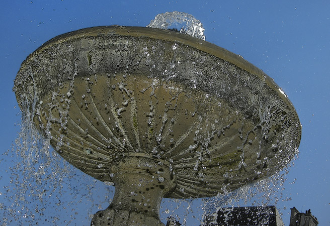 De l’eau jaillissant d’une fontaine dans la place des Vosges.