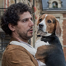 Un homme qui tient son chien dans ses bras dans la place des Vosges.