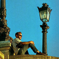 Un jeune homme regarde un coucher de soleil depuis le pont Neuf.