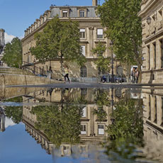 La caserne Napoléon et la place Baudoyer reflétées dans une flaque d’eau sur la rue François-Miron.