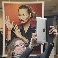 A woman taking a picture with an Apple iPad on rue des Rosiers.