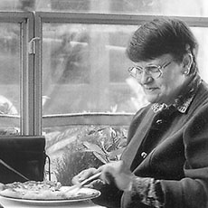 Une femme en train de déjeuner avec des moineaux dans la place Joachim-du-Bellay.