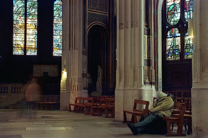 A homeless man sleeping on a pew in église Saint-Gervais.