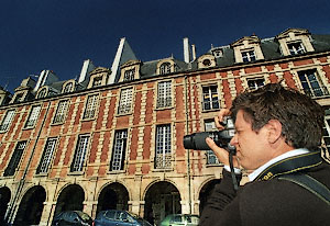 A photography student looking at place des Vosges through the viewfinder of his camera.