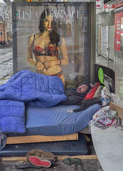 A homeless man sleeping in front of an advertising poster for Lise Charmel bras and lingerie.