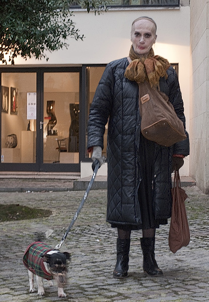 A middle-aged crossdressing man with his dog in the Marais.