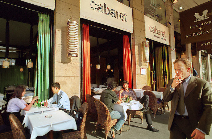 The façade and sidewalk tables of Le Cabaret, next to the Louvre des Antiquaires shopping mall.
