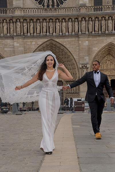 Naz and Mikael Oliver walking away from Notre-Dame in their wedding clothes.